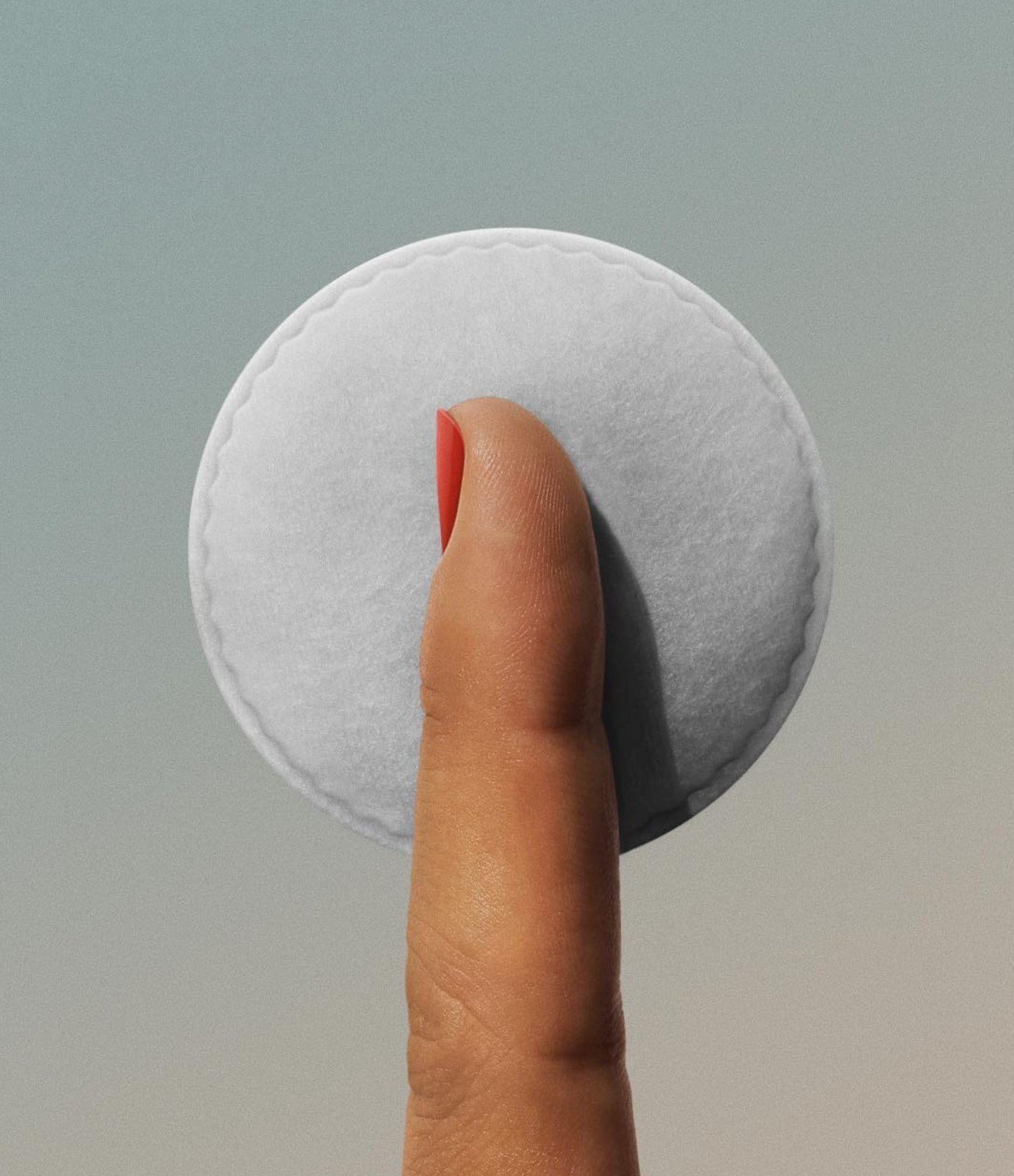 Finger holding a cotton pad against a soft grey-blue background, representing gentle skincare for stress-related acne
