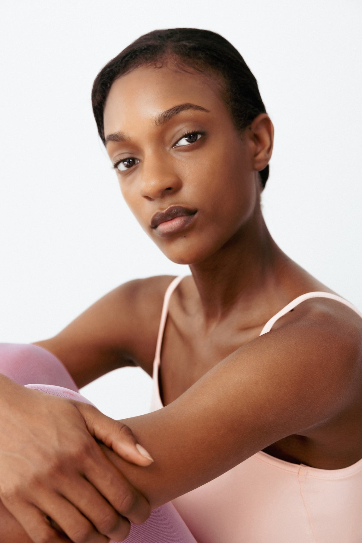 Young woman with clear skin looking directly at the camera against a white background, representing confidence after hormonal acne treatment